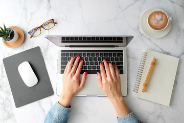 A person typing on a computer with a notebook next to the keyboard.